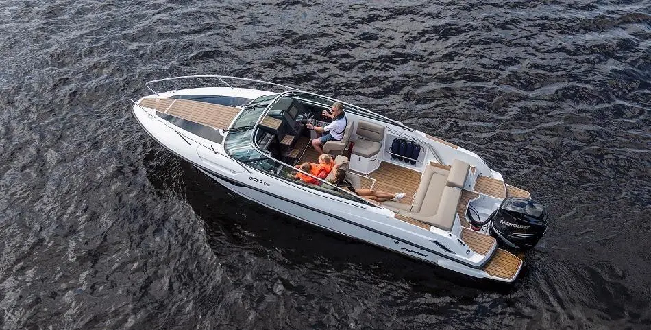 People enjoying a boat ride on a sleek motorboat with leather seating and a Mercury engine, surrounded by calm water.